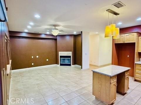 kitchen featuring ceiling fan, a kitchen island, and hanging light fixtures