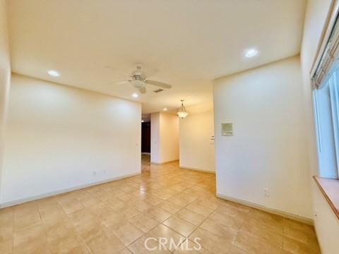 tiled empty room featuring ceiling fan