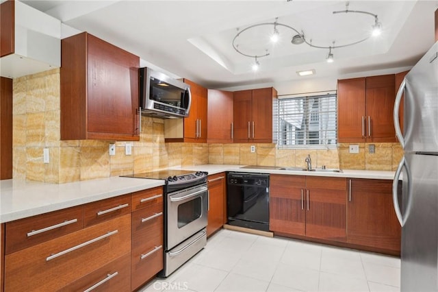 kitchen featuring a tray ceiling, decorative backsplash, sink, and appliances with stainless steel finishes