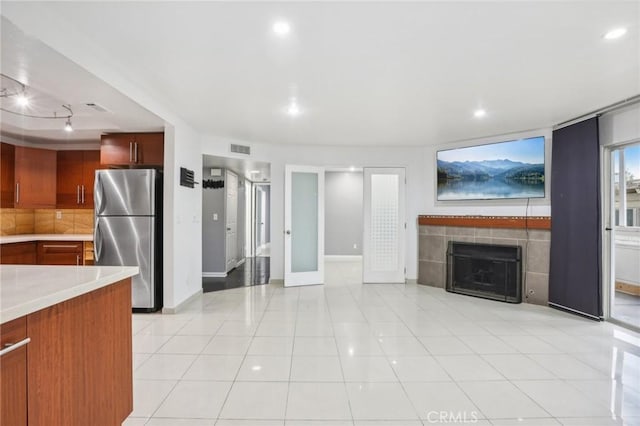 kitchen featuring stainless steel refrigerator, a fireplace, and light tile patterned flooring