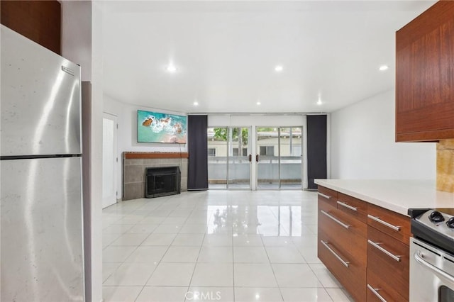 kitchen with a fireplace, light tile patterned flooring, a wall of windows, and stainless steel appliances