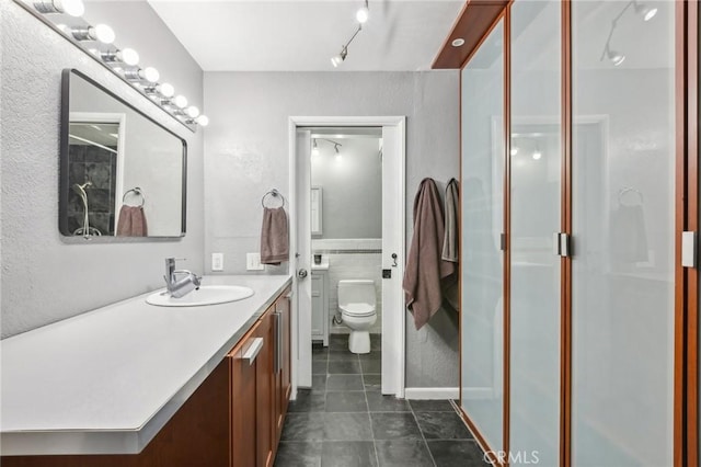 bathroom with a shower, tile patterned floors, vanity, and toilet