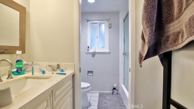 bathroom featuring tile patterned flooring, vanity, a shower with shower door, and toilet