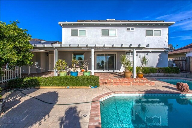 rear view of house featuring a patio area and a fenced in pool