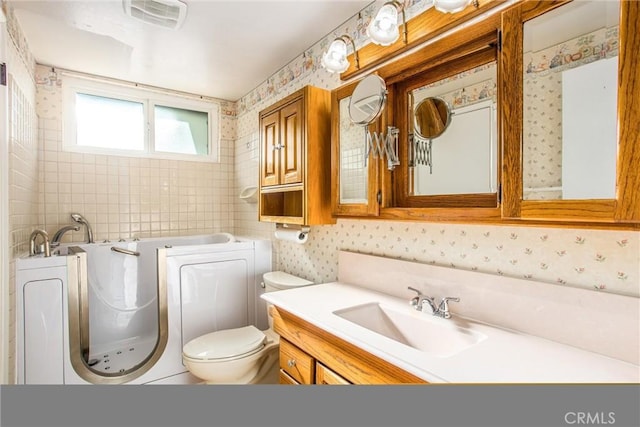 bathroom featuring vanity, toilet, and a tub to relax in