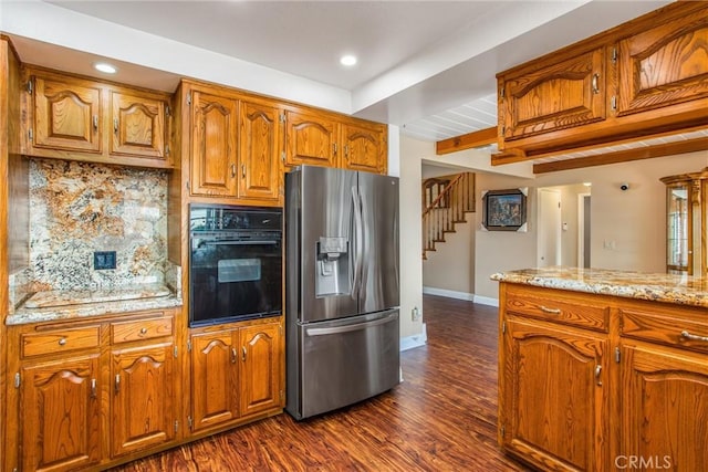 kitchen with light stone countertops, stainless steel refrigerator with ice dispenser, dark hardwood / wood-style flooring, beamed ceiling, and oven