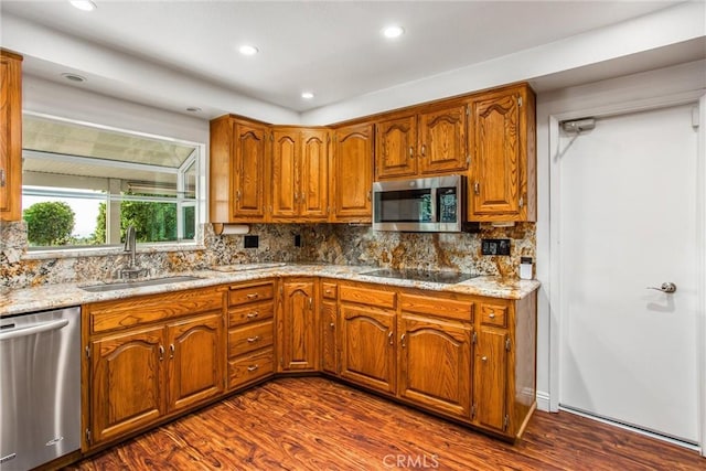 kitchen featuring dark wood-type flooring, sink, light stone countertops, appliances with stainless steel finishes, and tasteful backsplash