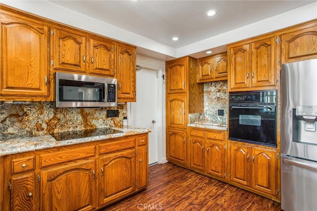 kitchen featuring light stone countertops, backsplash, dark wood-type flooring, and black appliances