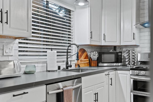 kitchen with white cabinets, wall chimney range hood, sink, decorative backsplash, and appliances with stainless steel finishes