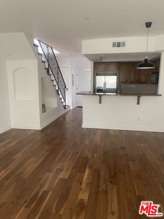 unfurnished living room featuring sink and dark wood-type flooring