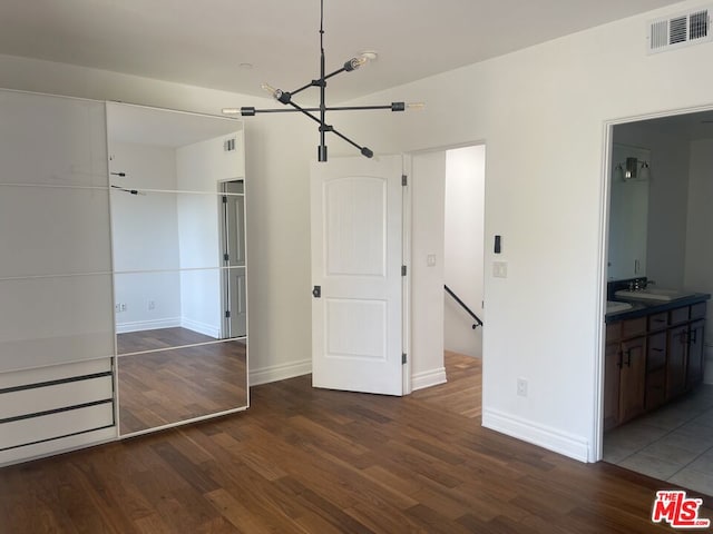 unfurnished bedroom with dark hardwood / wood-style flooring, ensuite bath, a notable chandelier, and sink