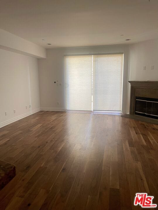 unfurnished living room with plenty of natural light and dark wood-type flooring