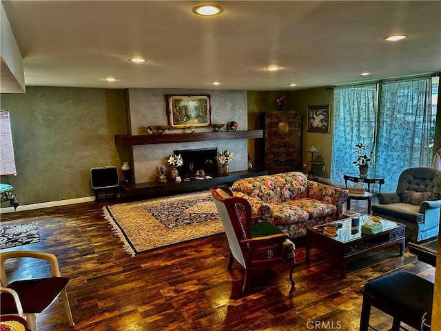 living room with dark hardwood / wood-style flooring and a large fireplace