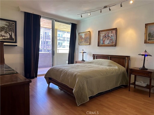 bedroom featuring crown molding, access to exterior, hardwood / wood-style flooring, and rail lighting