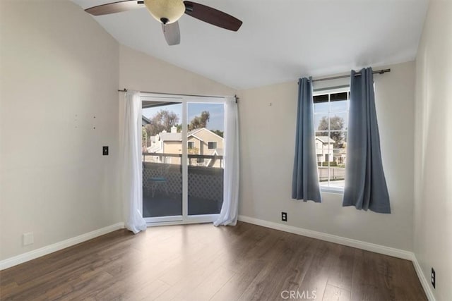 spare room featuring ceiling fan, dark wood-type flooring, lofted ceiling, and a healthy amount of sunlight