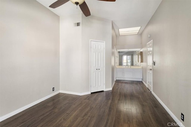 corridor with high vaulted ceiling, a skylight, dark hardwood / wood-style flooring, and sink