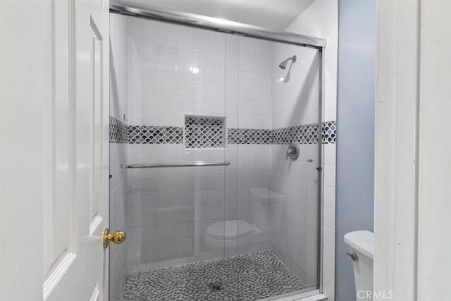 bathroom featuring toilet and a shower with shower door