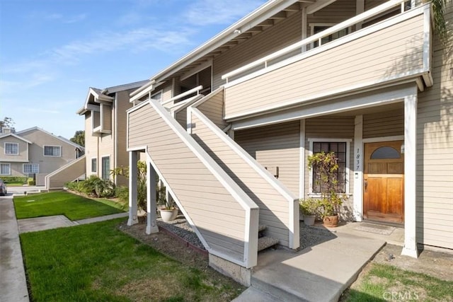 view of side of property featuring a balcony and a lawn