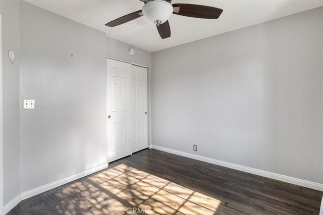 unfurnished bedroom with dark wood-type flooring, a closet, and ceiling fan