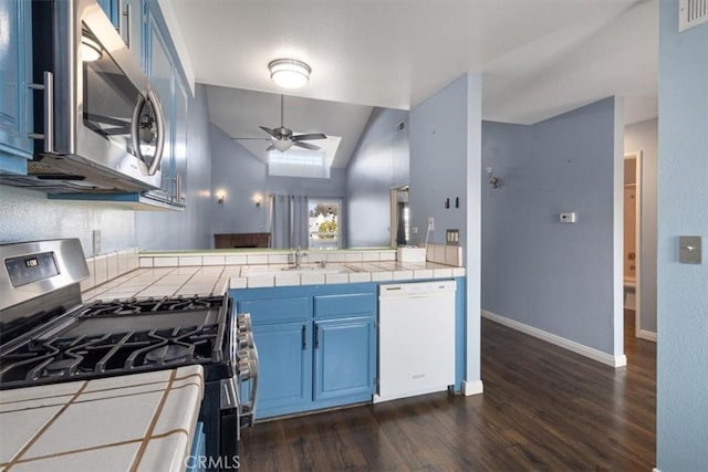 kitchen with tile counters, stainless steel appliances, vaulted ceiling, ceiling fan, and blue cabinets