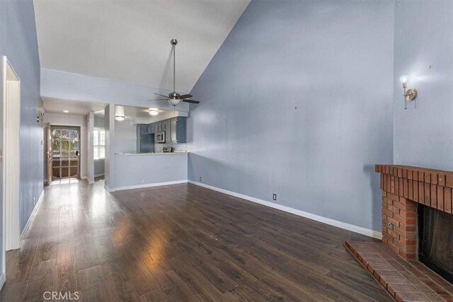 unfurnished living room with high vaulted ceiling, dark wood-type flooring, ceiling fan, and a fireplace