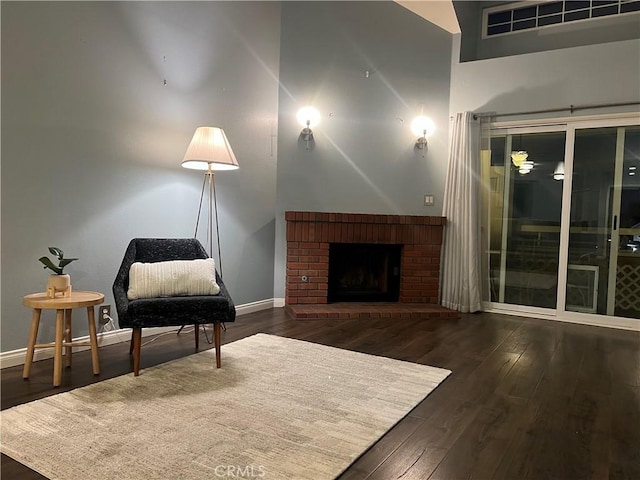 living area featuring a brick fireplace and dark hardwood / wood-style floors