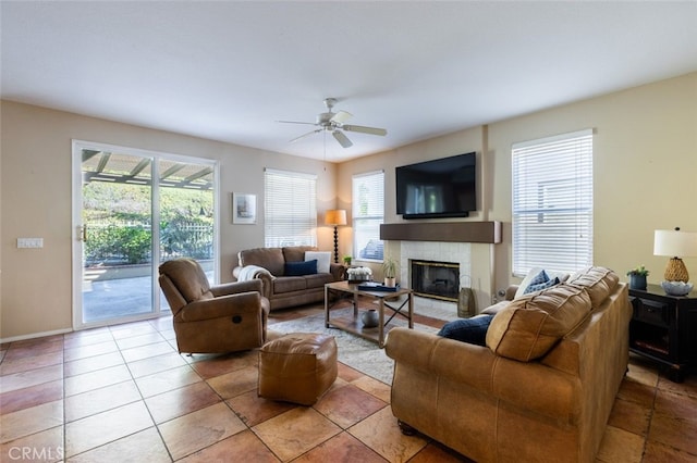 living room featuring ceiling fan, a healthy amount of sunlight, light tile patterned flooring, and a fireplace