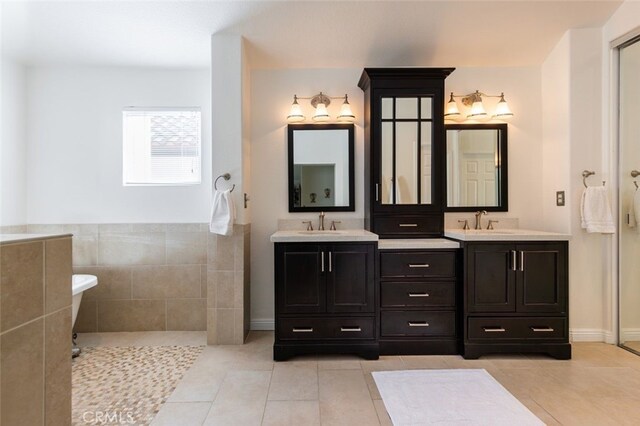 bathroom with tile patterned flooring, vanity, tile walls, and a washtub