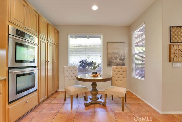 dining area with a wealth of natural light, light tile patterned flooring, and baseboards