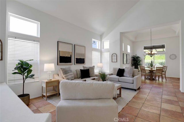 living room featuring high vaulted ceiling, light tile patterned floors, a notable chandelier, and a healthy amount of sunlight