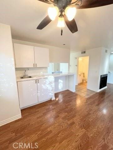 kitchen with light countertops, ceiling fan, light wood finished floors, a sink, and white cabinetry