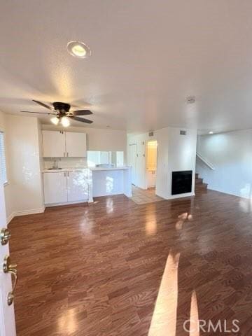 unfurnished living room featuring dark hardwood / wood-style flooring and ceiling fan