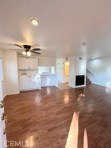 unfurnished living room featuring wood finished floors, a ceiling fan, and baseboards