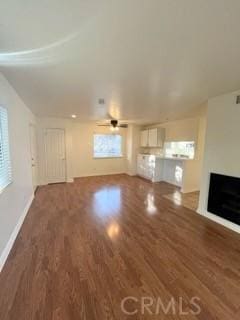 unfurnished living room featuring baseboards, wood finished floors, ceiling fan, and a fireplace