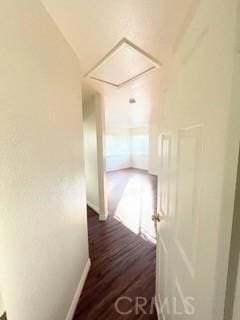 hall featuring baseboards, attic access, and dark wood-style flooring