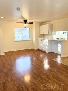 unfurnished living room featuring ceiling fan and dark wood-type flooring