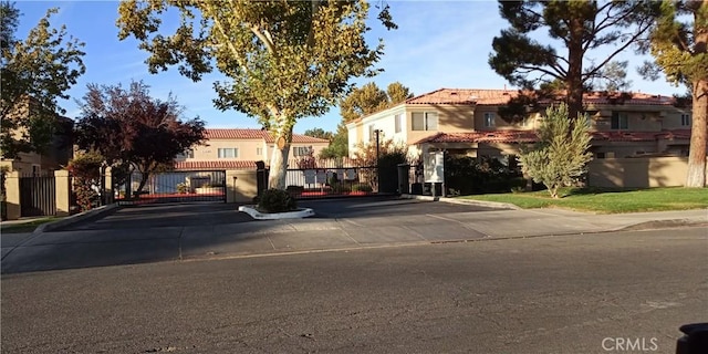 multi unit property with stucco siding, a gate, and a tile roof
