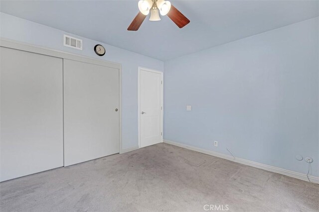 unfurnished bedroom featuring ceiling fan, a closet, and light carpet