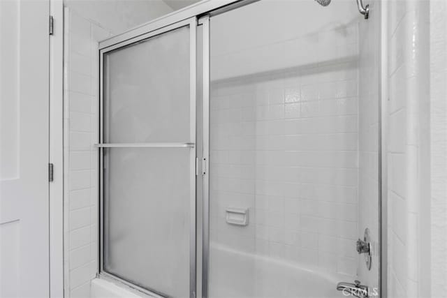 bathroom featuring bath / shower combo with glass door