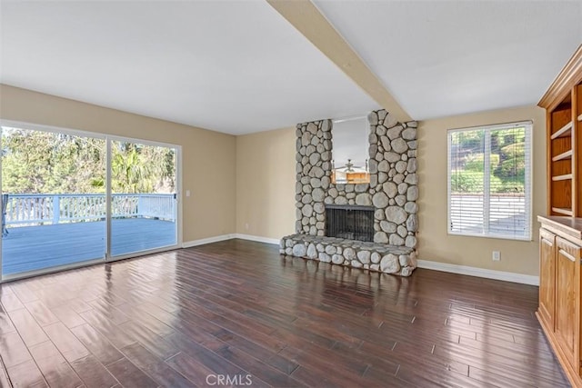 unfurnished living room with dark hardwood / wood-style flooring, a healthy amount of sunlight, and a stone fireplace