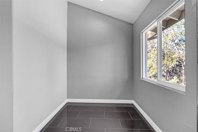 spare room featuring a wealth of natural light and dark tile patterned floors