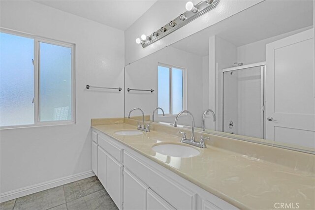 bathroom with a shower with door, vanity, and tile patterned flooring