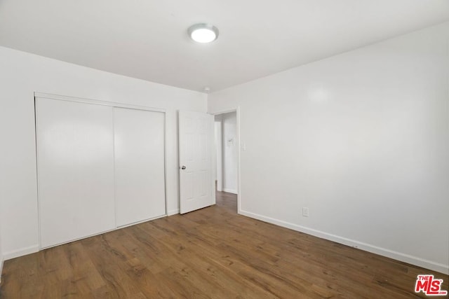 unfurnished bedroom featuring dark hardwood / wood-style floors and a closet