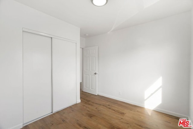 unfurnished bedroom with hardwood / wood-style floors and a closet