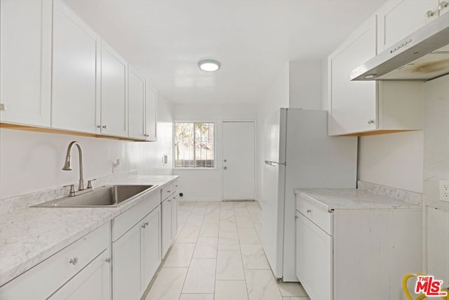 kitchen featuring light stone counters, ventilation hood, sink, white fridge, and white cabinetry