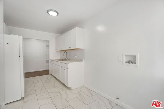 kitchen featuring white refrigerator, white cabinetry, and sink