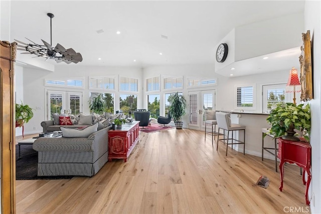 living room with ceiling fan, french doors, a healthy amount of sunlight, and light wood-type flooring