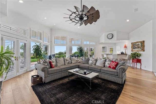 living room with french doors, ceiling fan, vaulted ceiling, and light wood-type flooring