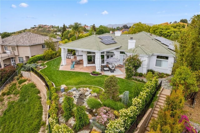 rear view of property with a lawn, a patio area, and solar panels