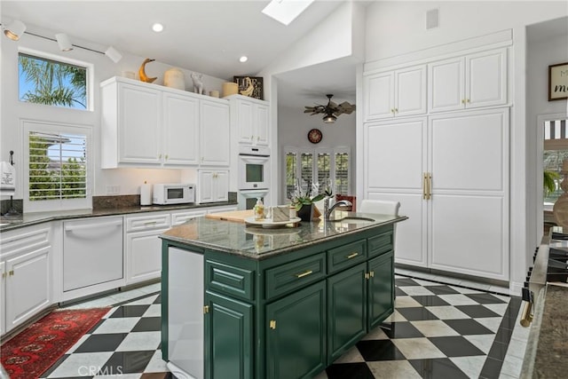 kitchen with a kitchen island, green cabinets, white cabinets, and white appliances